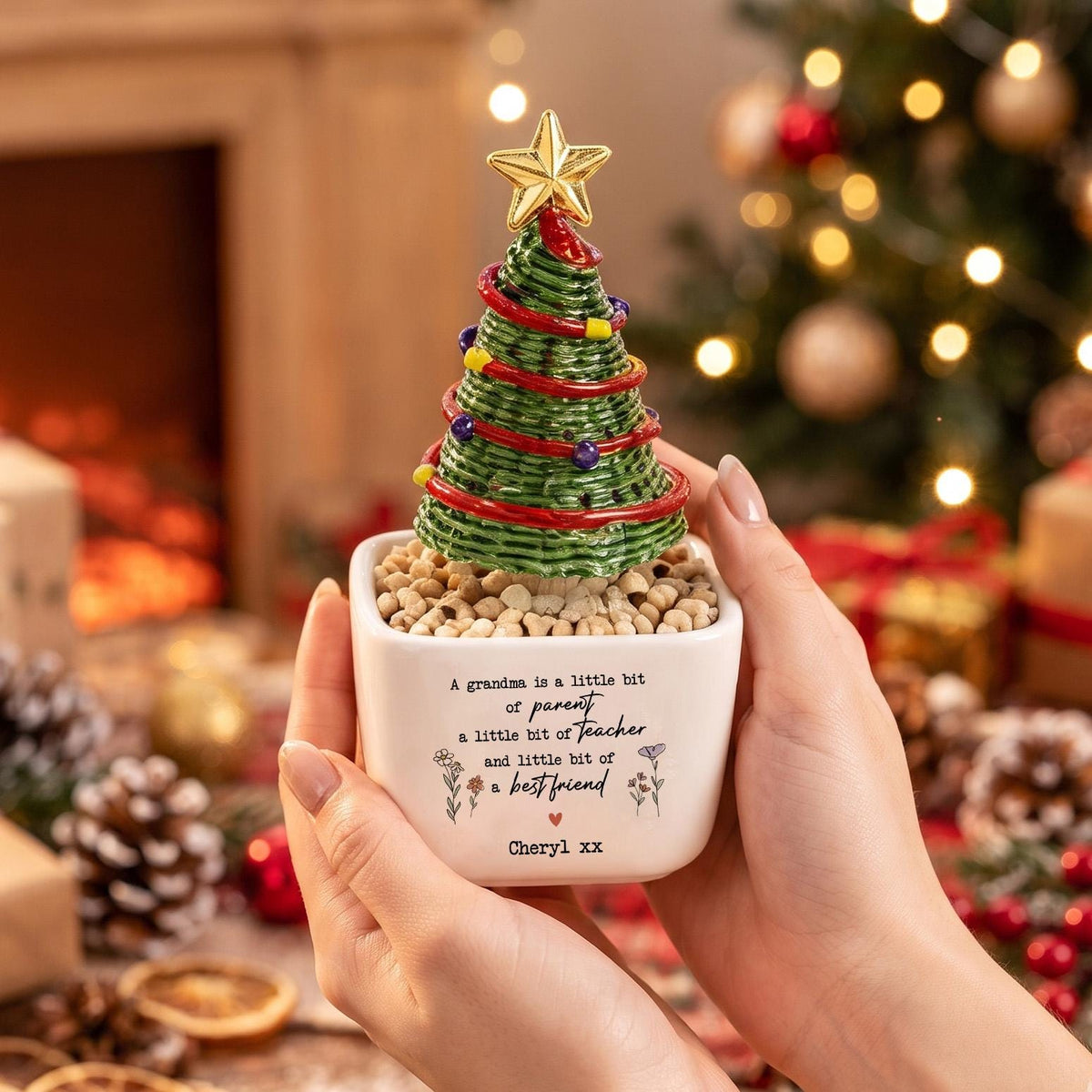 May include: A small ceramic planter with a white square base containing a green textured Christmas tree ornament topped with a gold star. The planter features the text: A grandma is a little bit of parent a little bit of teacher and little bit of best friend, Cheryl xx.