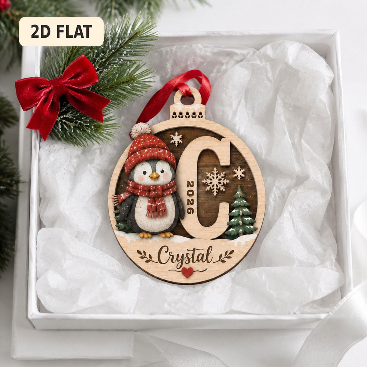 May include: A round wooden Christmas ornament featuring a penguin wearing a red knit hat and scarf, a large letter C, the year 2026, a small green pine tree, and the name Crystal in script. The ornament has a red ribbon hanger and a small red heart.