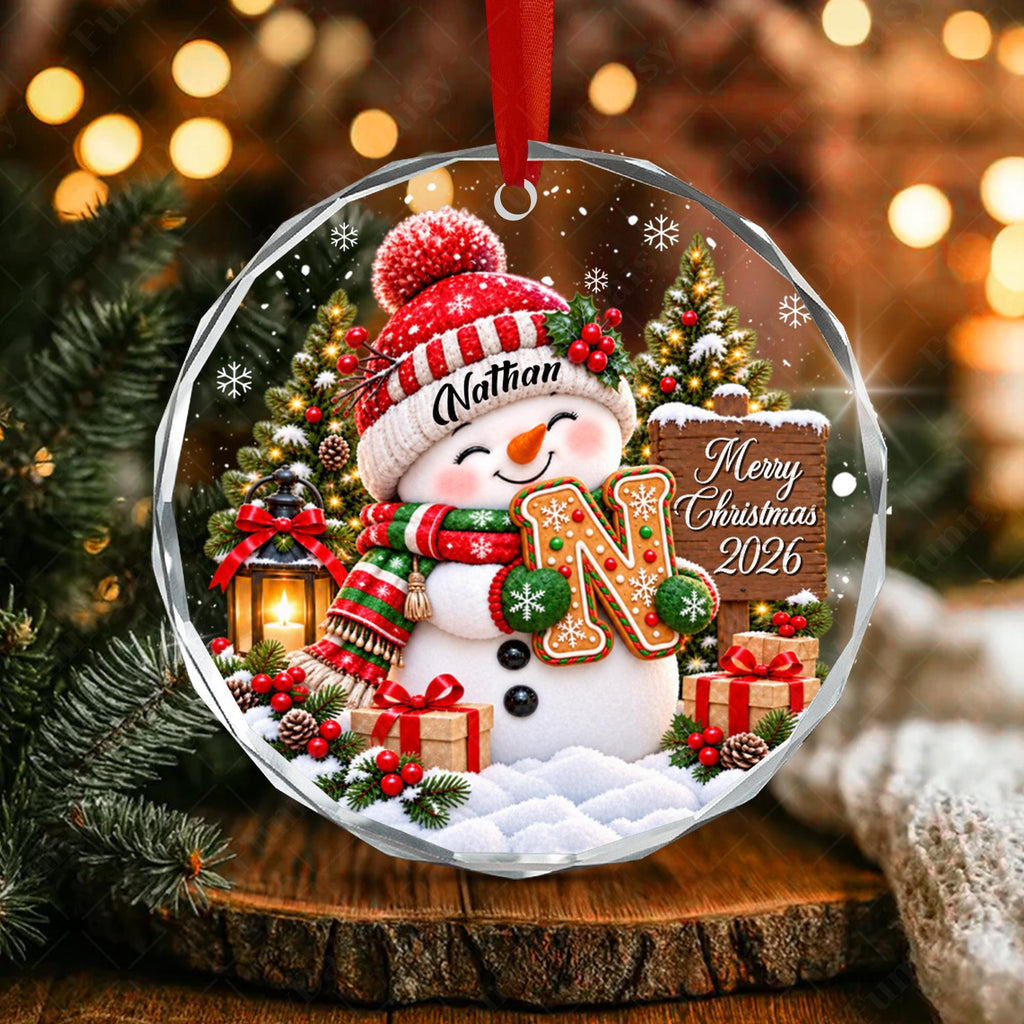 May include: A round, clear acrylic Christmas ornament featuring a snowman wearing a red and white knit hat with the name Nathan, a green and red scarf, and holding a gingerbread letter N. A wooden sign reads Merry Christmas 2026.