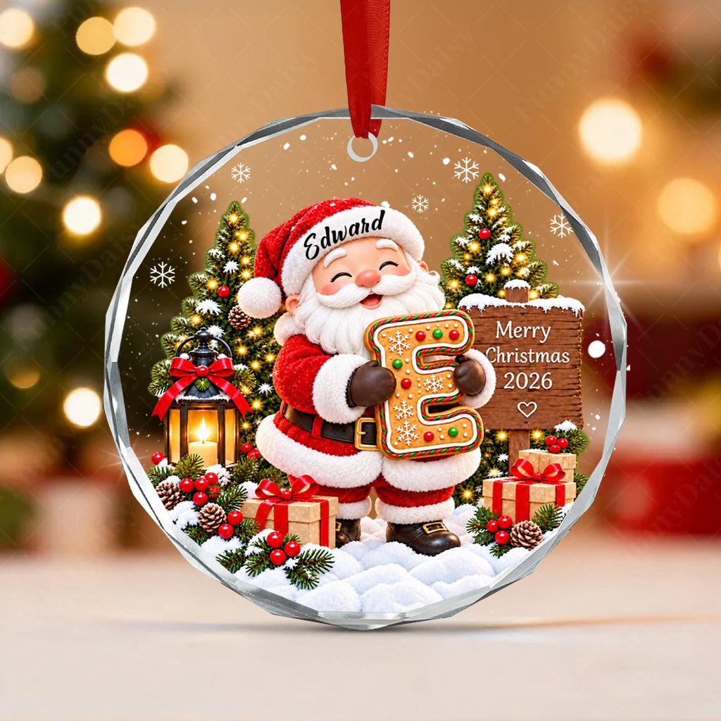 May include: A round, clear acrylic ornament featuring a festive illustration of Santa Claus holding a gingerbread letter E. The design includes a wooden sign with the text Merry Christmas 2026, a lantern, gifts, and pine trees. The name Edward is printed on Santa's hat.