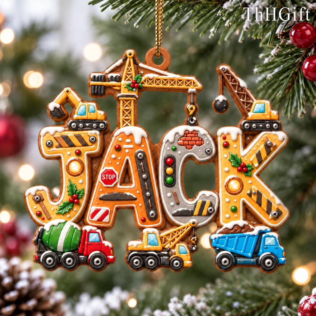 May include: A Christmas tree ornament shaped like the name JACK, featuring construction-themed letters with yellow cranes, a red cement mixer, a yellow excavator, a blue dump truck, a stop sign, and green holly accents, all topped with white snow.