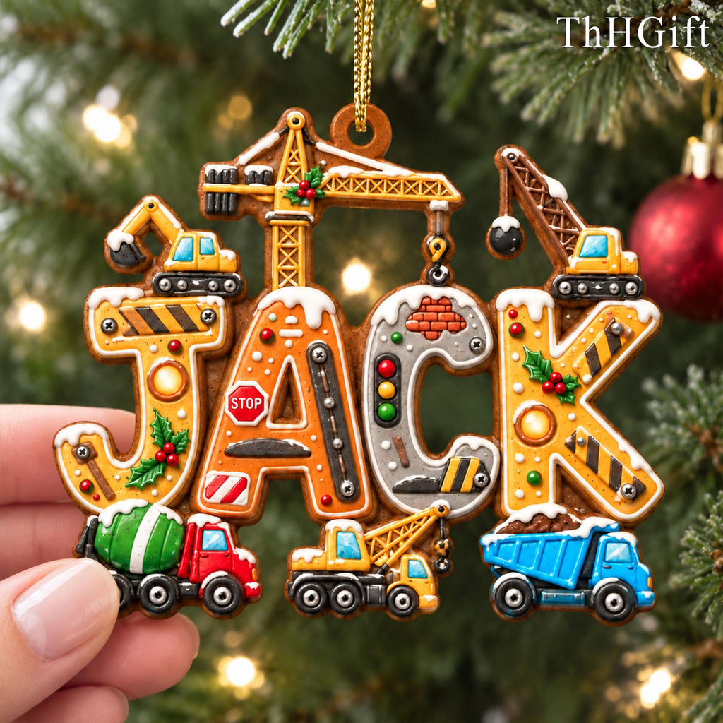May include: A personalized Christmas ornament shaped like the name JACK, featuring construction vehicles, a stop sign, traffic lights, and brick patterns. The letters are decorated with snow, holly, and metallic accents, hanging from a gold cord.
