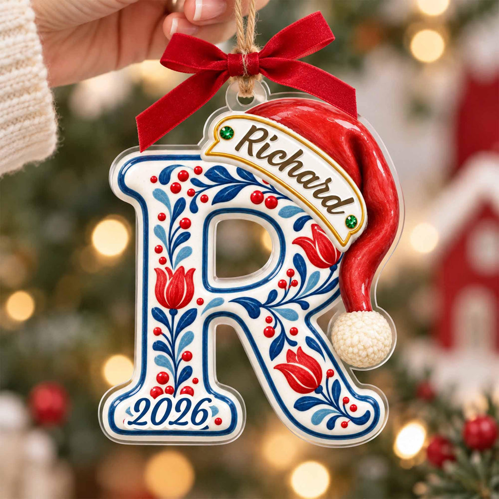 May include: A clear acrylic letter R Christmas ornament featuring a red Santa hat, a red ribbon bow, and blue and red floral patterns. The name Richard is printed on a banner across the top, and the year 2026 is printed at the bottom of the letter.
