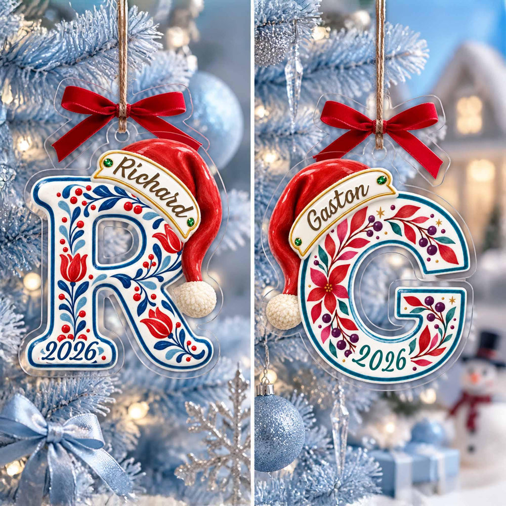 May include: Two clear acrylic Christmas ornaments shaped like the letters R and G. Each features a red Santa hat, a red ribbon bow, and a floral pattern in red, blue, and green. The names Richard and Gaston are printed on banners, with 2026 below.