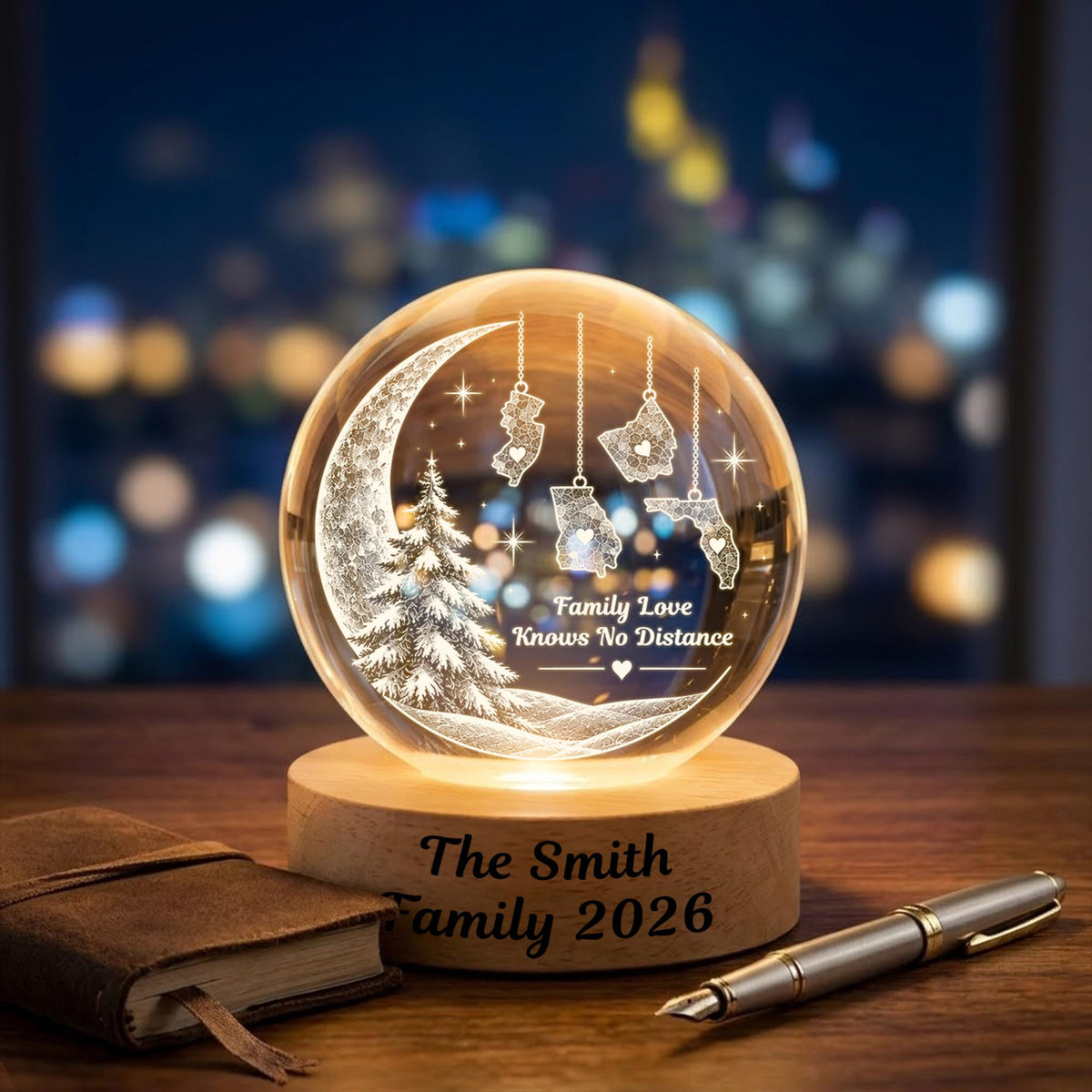 May include: A clear glass sphere night light on a round wooden base engraved with The Smith Family 2026. The sphere features an etched crescent moon, a pine tree, and four US state map outlines hanging from chains with the text Family Love Knows No Distance.