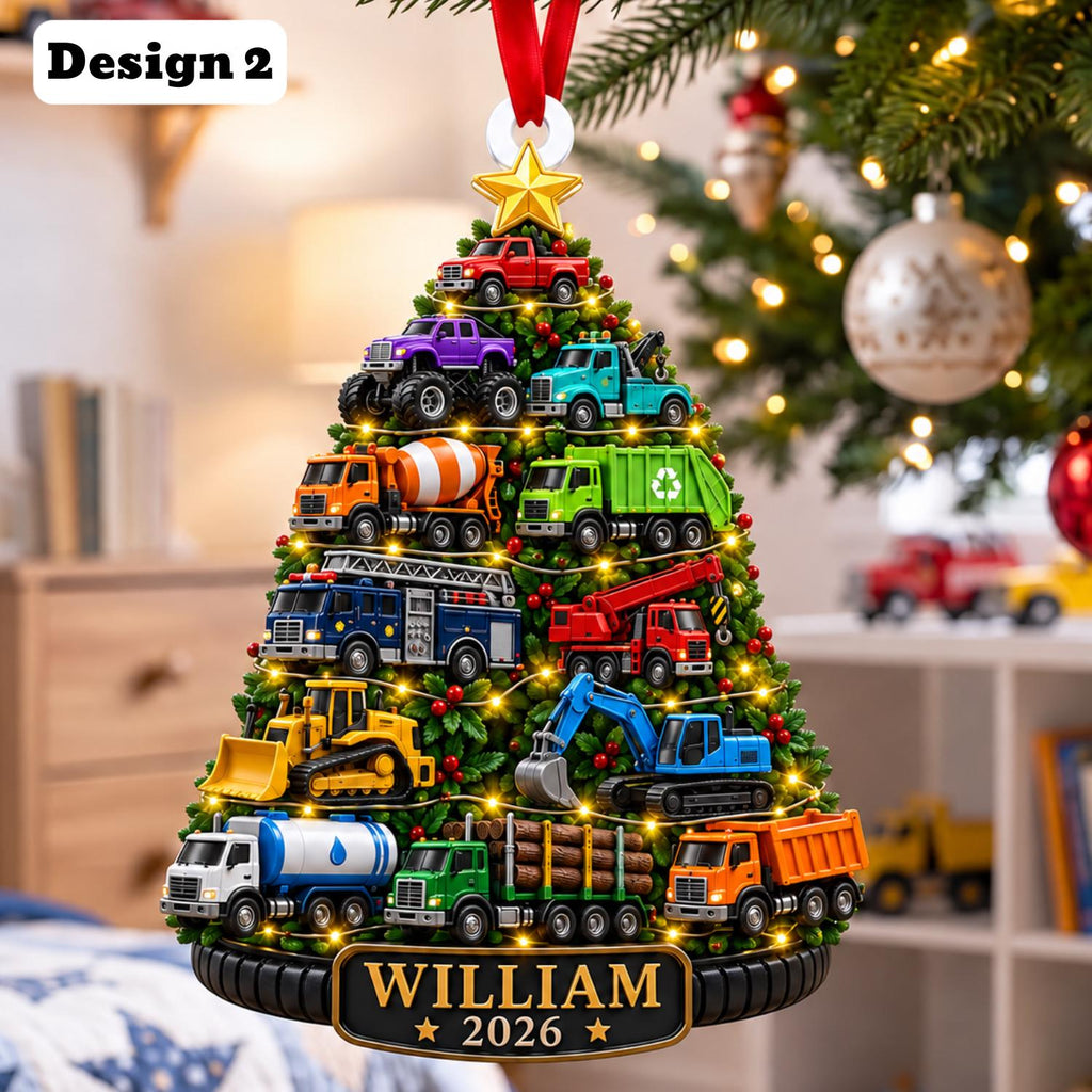 May include: A Christmas tree-shaped ornament featuring various construction and emergency vehicles, including a red truck, purple monster truck, cement mixer, fire truck, and excavator. The base displays the text WILLIAM 2026 with a gold star on top.