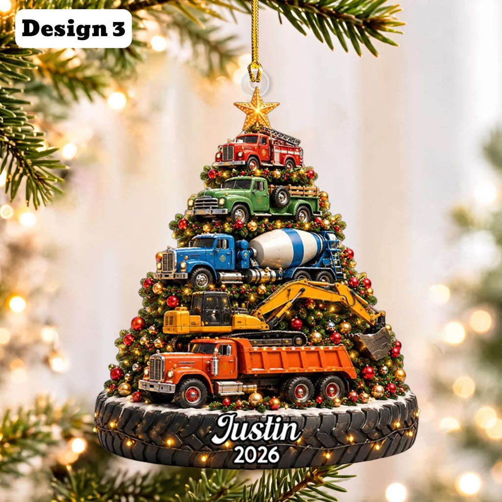 May include: A Christmas tree-shaped ornament featuring stacked construction vehicles including a red fire truck, green pickup, blue cement mixer, yellow excavator, and orange dump truck. The base is a black tire with the text Justin 2026.