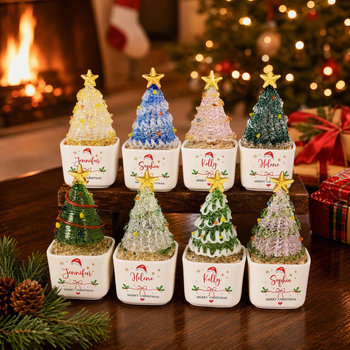May include: Eight miniature Christmas tree ornaments in square white ceramic pots. Each tree features a unique color and texture, topped with a gold star. The pots are personalized with names including Jennifer, Sophia, Kelly, and Helene.