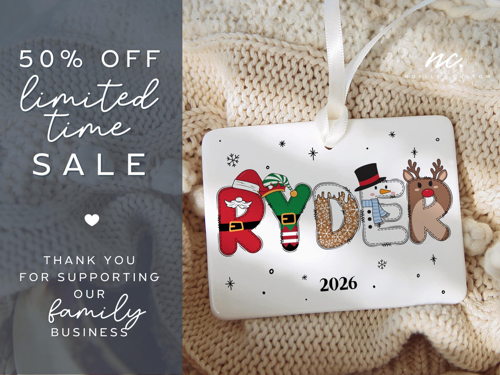 May include: A rectangular white ceramic Christmas ornament featuring the name RYDER in festive holiday-themed letters, including a Santa suit, elf attire, gingerbread, snowman, and reindeer. The year 2026 is printed below, and a white ribbon is attached.