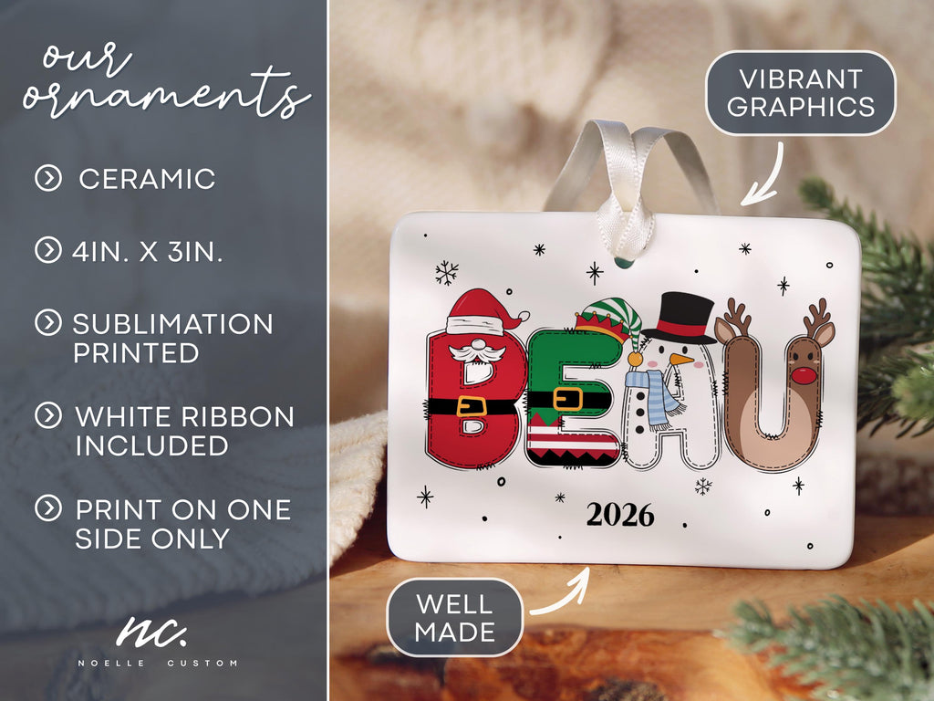May include: A rectangular white ceramic ornament measuring 4 inches by 3 inches, featuring the name BEAU spelled out in festive holiday characters including Santa, an elf, a snowman, and a reindeer, with the year 2026 and a white ribbon.