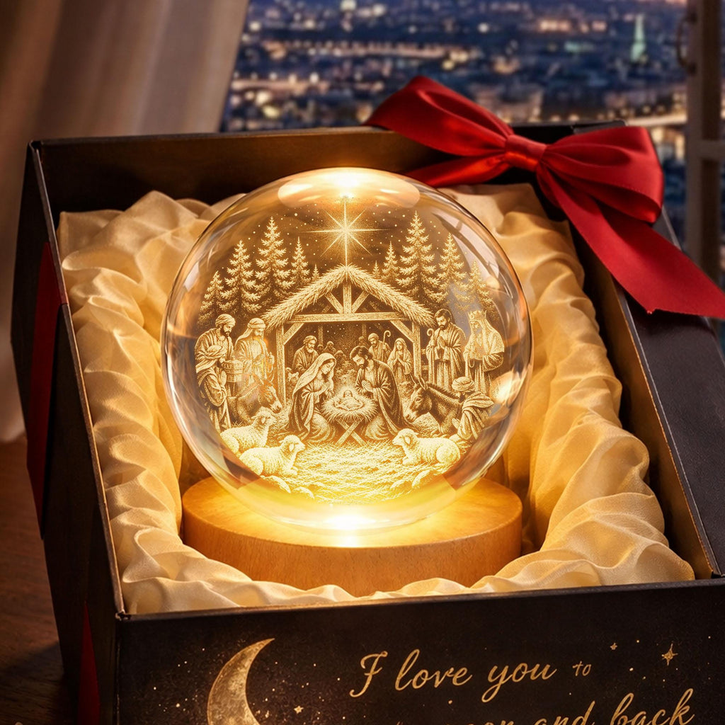 May include: A clear glass sphere featuring a 3D laser-engraved nativity scene with a star, figures, and animals, illuminated from a circular wooden base. The sphere is nestled in a black gift box lined with cream fabric and a red ribbon bow.