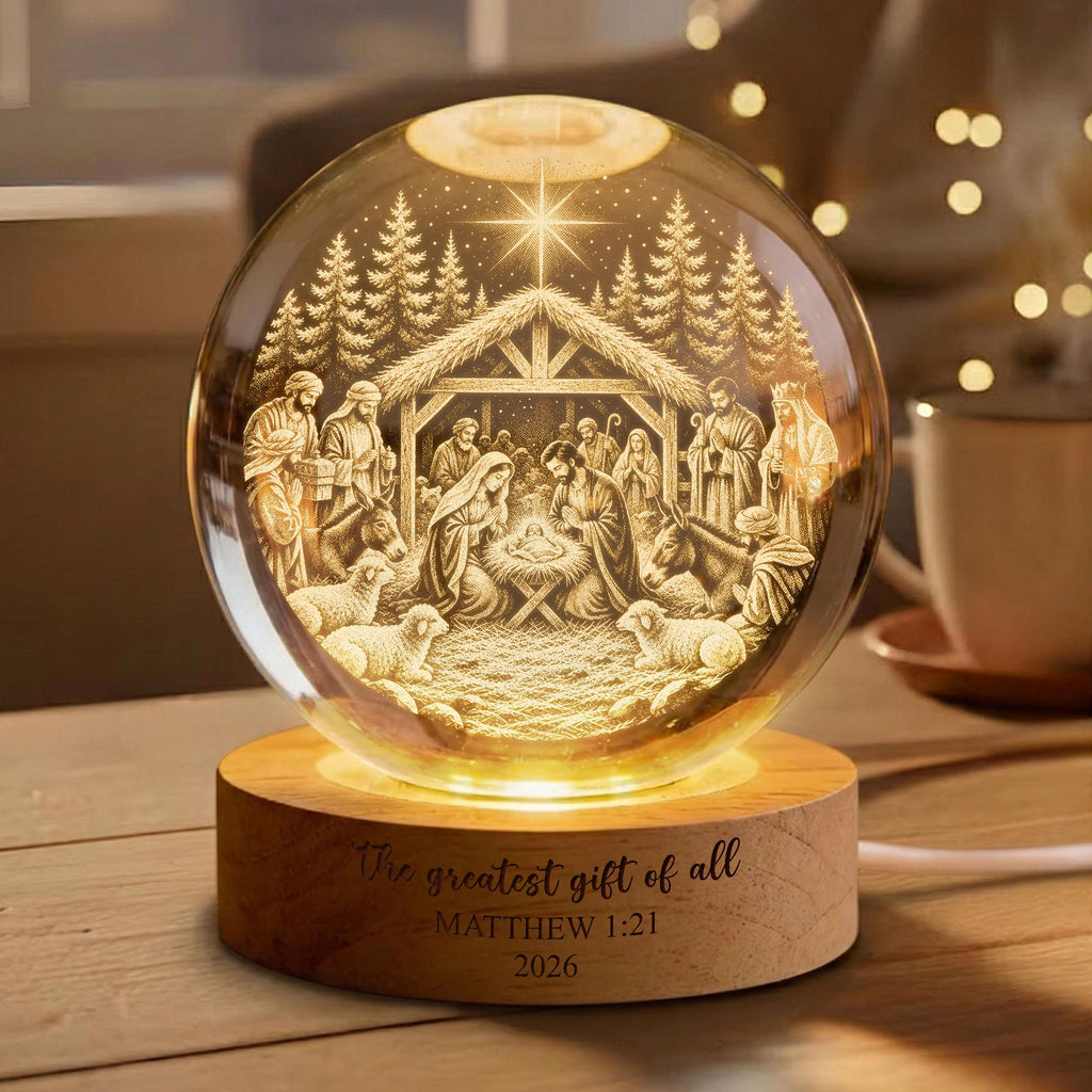 May include: A spherical glass night light featuring an internal 3D laser-etched nativity scene with a star above a stable. The light sits on a round wooden base engraved with the text The greatest gift of all - MATTHEW 1:21 2026.