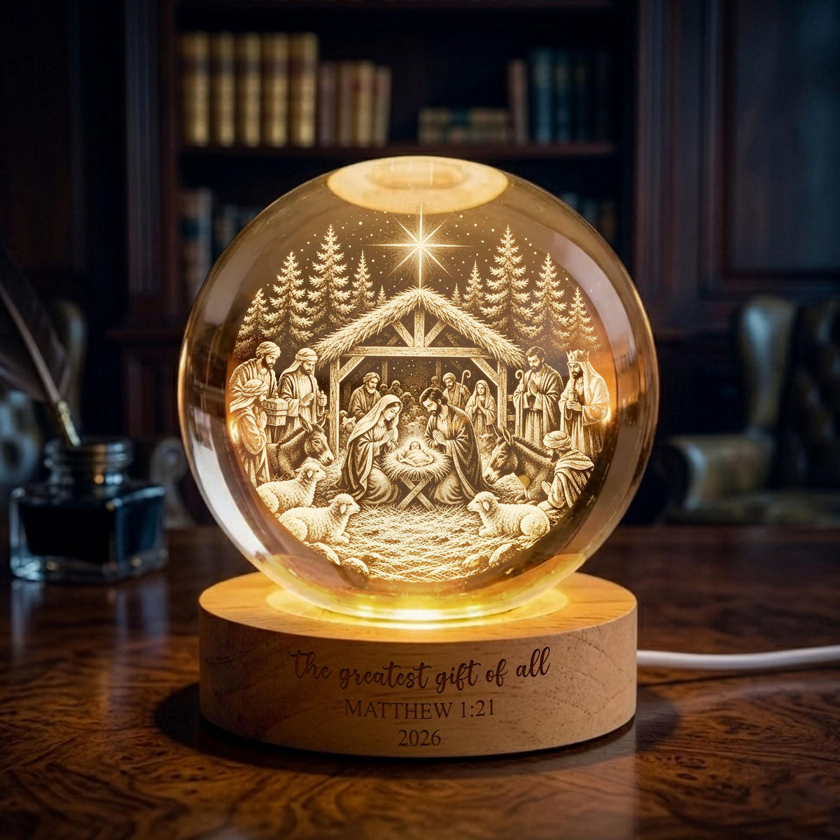 May include: A spherical glass ornament featuring an internal laser-etched nativity scene with a star, trees, and figures, illuminated from below by a circular wooden base engraved with the text The greatest gift of all MATTHEW 1:21 2026.