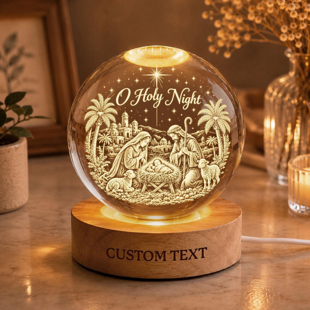 May include: A clear glass sphere lamp featuring an etched nativity scene with the text O Holy Night and a star above. The sphere rests on a round wooden base with the text CUSTOM TEXT engraved on the front, illuminated from below by a light.