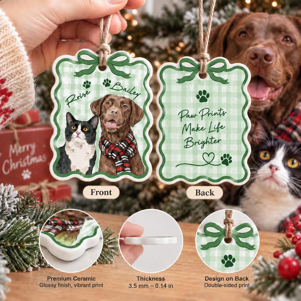 May include: A scalloped ceramic ornament with a green gingham pattern. The front features a cat and a brown dog wearing a red and black scarf with the names Roise and Bailey. The back displays the text Paw Prints Make Life Brighter with paw prints and a heart. It is 3.5 mm thick.