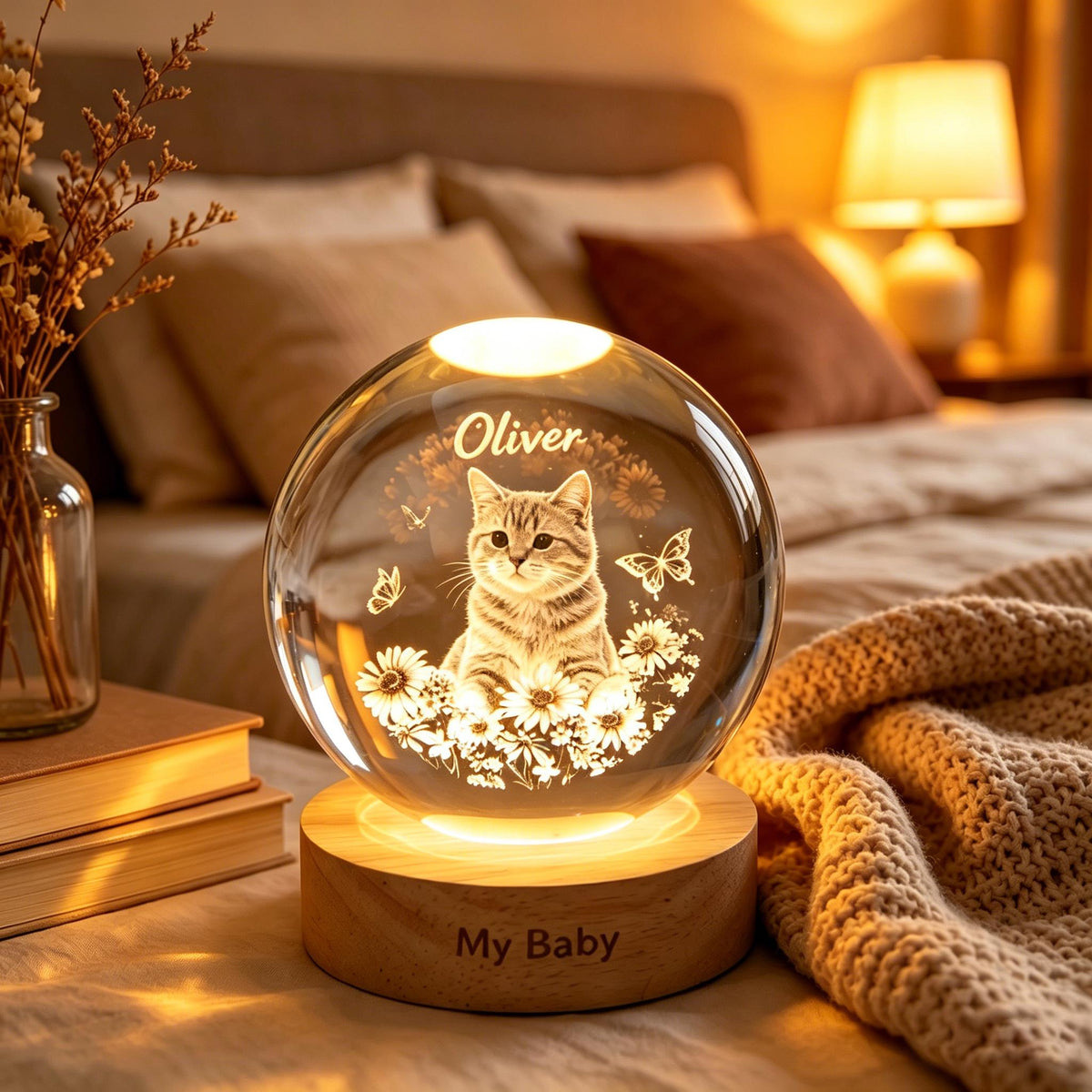 May include: A clear glass sphere lamp with a cat illustration, the name "Oliver", and the text "My Baby". The lamp sits on a wooden base and is surrounded by a warm, soft glow. The cat is surrounded by flowers and butterflies.