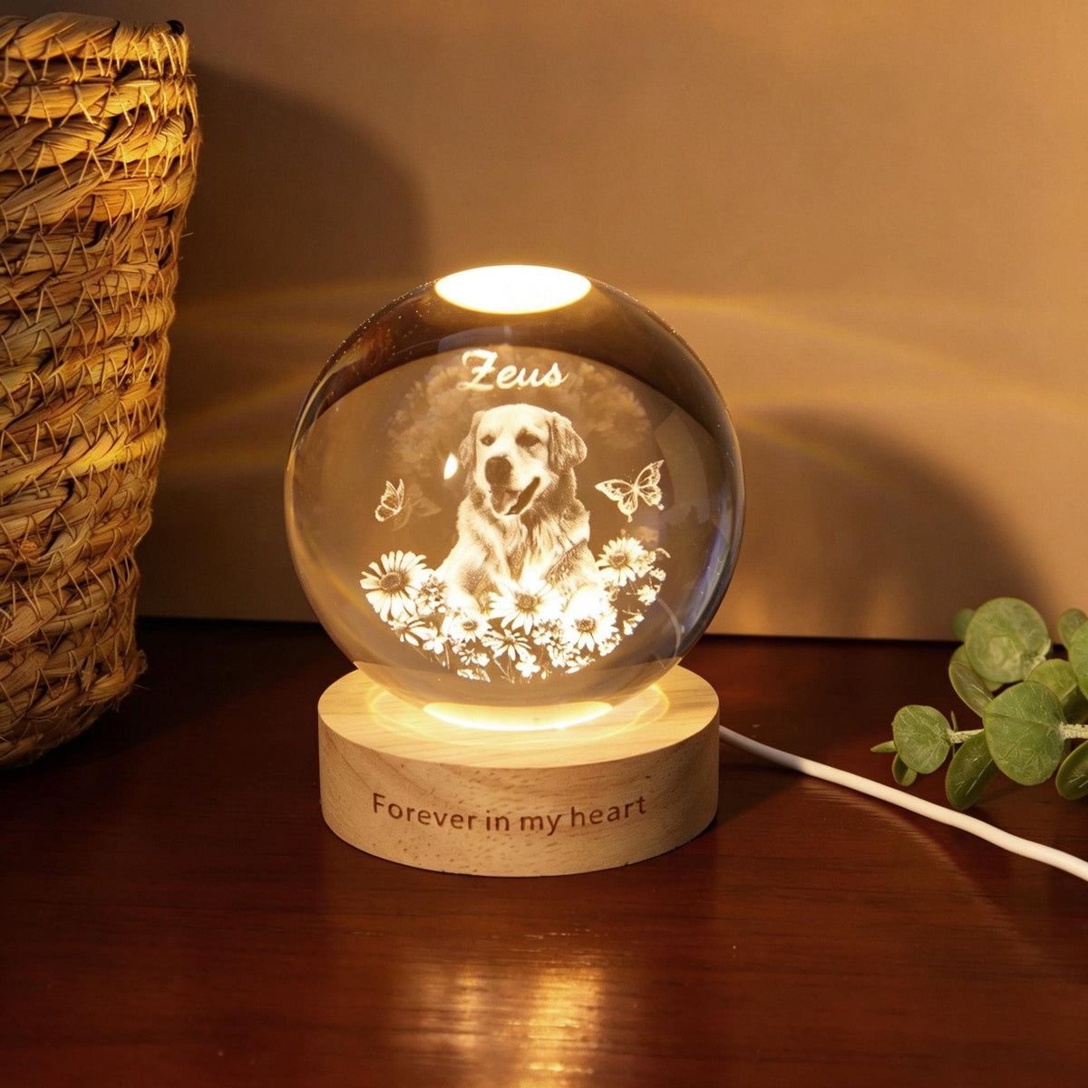 May include: A glowing crystal ball with a dog portrait, butterflies, and flowers. The base is wood with the text "Forever in my heart". The dog's name, "Zeus", is etched above the image. A white cord extends from the base.