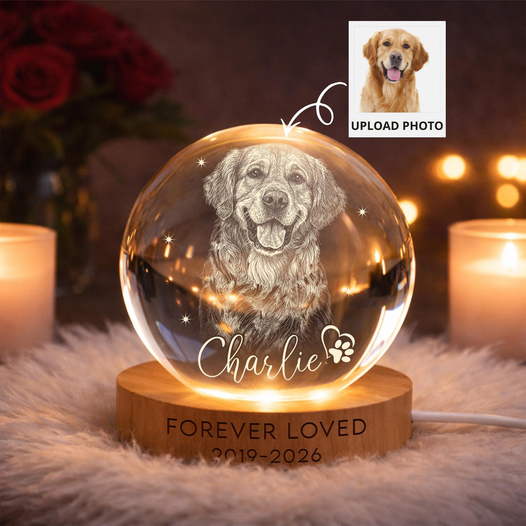 May include: A spherical glass paperweight featuring an etched portrait of a golden retriever, the name Charlie, and a paw print heart. It sits on a circular wooden base engraved with the text FOREVER LOVED 2019-2026, illuminated by internal lights.