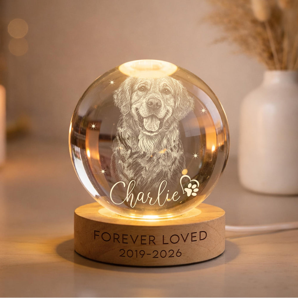 May include: A clear glass sphere lamp featuring an etched portrait of a dog, the name Charlie, and a paw print icon. The sphere rests on a circular wooden base engraved with the text FOREVER LOVED and the years 2019-2026, illuminated from below.