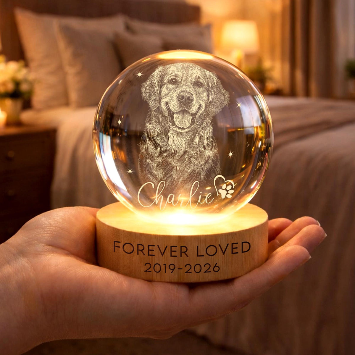 May include: A clear glass sphere featuring an etched portrait of a dog, the name Charlie, and a paw print. The sphere rests on a round wooden base illuminated from below, with the text FOREVER LOVED and the years 2019-2026 printed on the front.