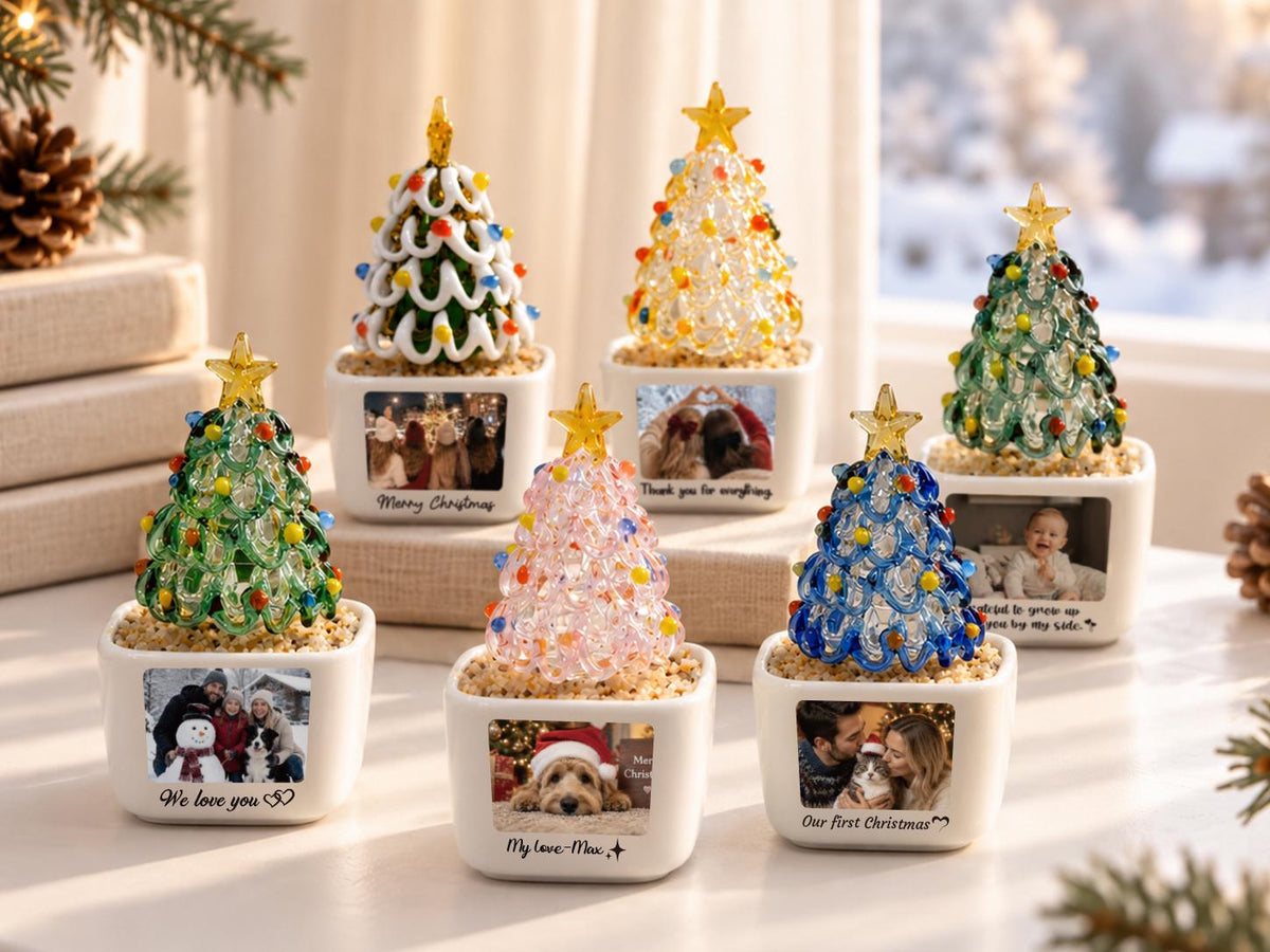 May include: Seven miniature glass Christmas trees in white square ceramic planters. Each tree features colorful glass beads and a yellow star topper. The planters display custom photographs and text, including phrases like We love you and My love-Max.