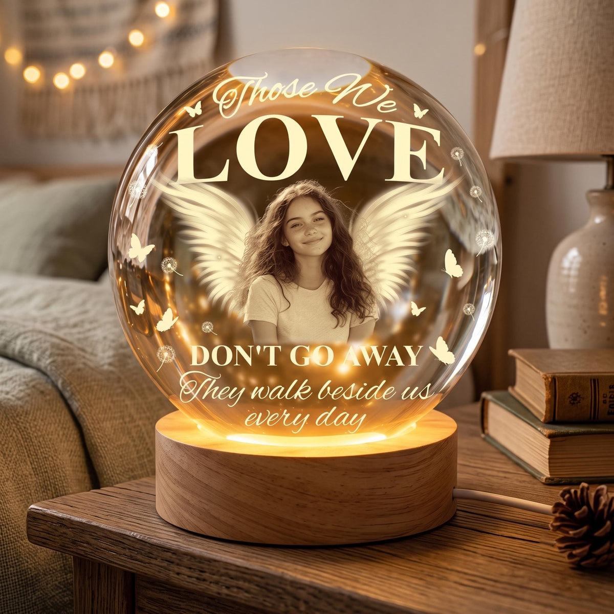 May include: A spherical glass lamp on a cylindrical wooden base featuring a photograph of a young person with angel wings. The glass is printed with the text: Those We LOVE DON'T GO AWAY They walk beside us every day, surrounded by butterflies.