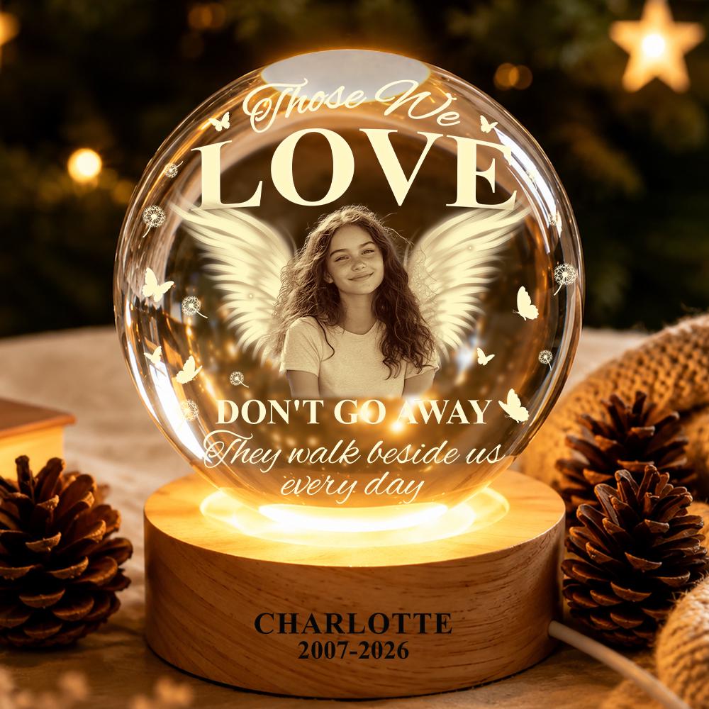 May include: A spherical glass memorial lamp on a round wooden base. The glass features a portrait of a young person with angel wings, surrounded by butterflies and dandelions. Text reads: Those We LOVE DON'T GO AWAY They walk beside us every day.