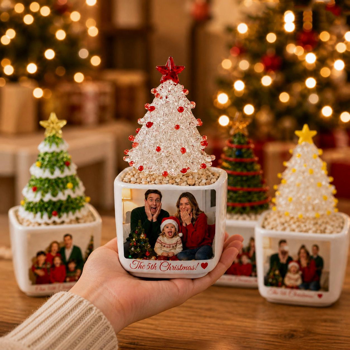 May include: A square white ceramic planter featuring a custom photo of a family and the text The 5th Christmas! with a red heart. The planter is topped with a clear, textured glass Christmas tree ornament with red accents and a red star topper.