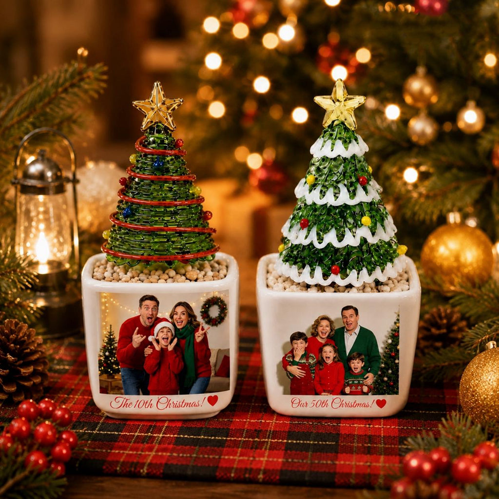 May include: Two square white ceramic planters, each topped with a decorative Christmas tree. The left tree is green wire with red accents and a gold star. The right tree is green with white snow and a gold star. Each planter features a family photo.
