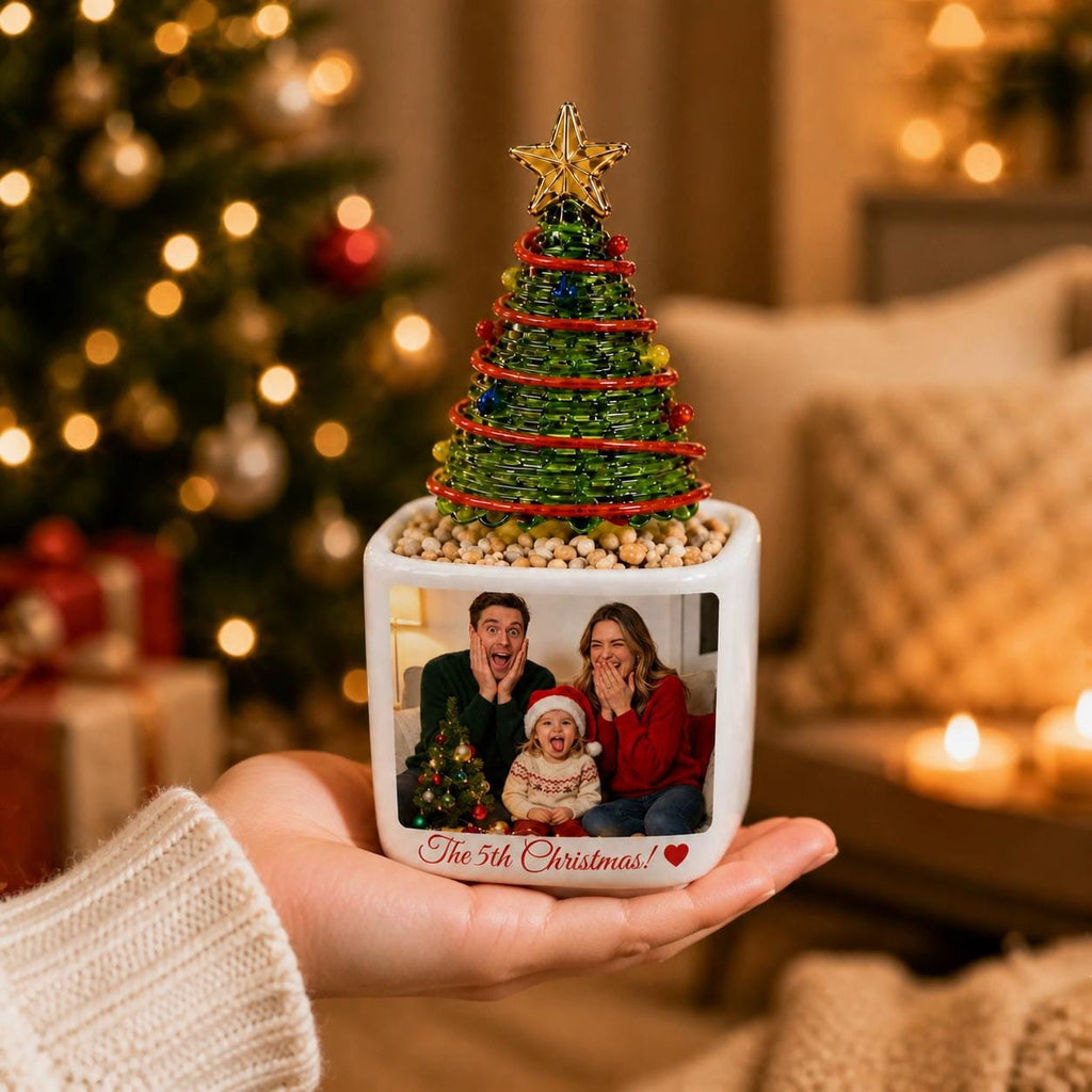 May include: A white ceramic square planter featuring a custom photo of a family of three on the front, with the text The 5th Christmas! and a red heart. A green wire-wrapped Christmas tree with a gold star topper sits in the planter.