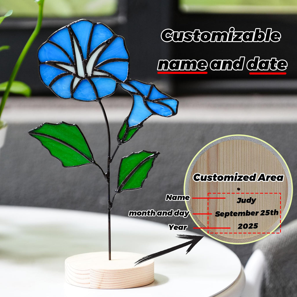 May include: A stained glass morning glory flower sculpture with blue petals and green leaves. The sculpture is mounted on a wooden base. The text "Customizable name and date" is visible. The example customization shows the name "Judy" and the date "September 25th, 2025".