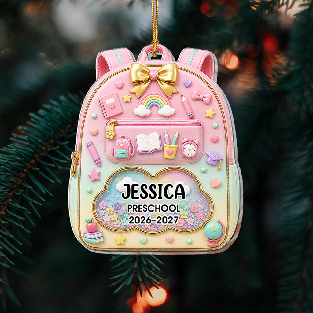 May include: A pastel-colored backpack ornament featuring a gold bow, school supplies, and a cloud-shaped window containing the text JESSICA, PRESCHOOL, 2026-2027, surrounded by colorful flowers and a gold hanging cord for display.
