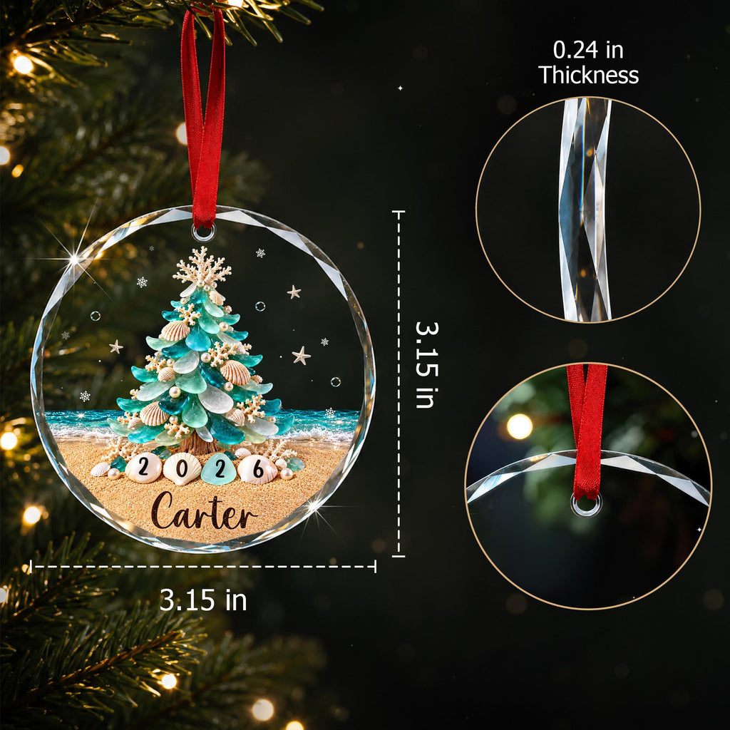 May include: A round, clear glass Christmas ornament featuring a beach-themed tree made of sea glass and seashells. The design includes the year 2026 and the name Carter. It measures 3.15 inches in diameter with a 0.24 inch thickness and a red ribbon.