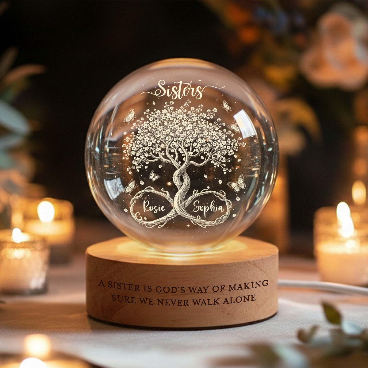May include: A clear glass sphere resting on a cylindrical wooden base. The sphere features an etched tree with butterflies and the text "Sisters", "Rosie", and "Sophia". The wooden base is engraved with "A SISTER IS GOD'S WAY OF MAKING SURE WE NEVER WALK ALONE".