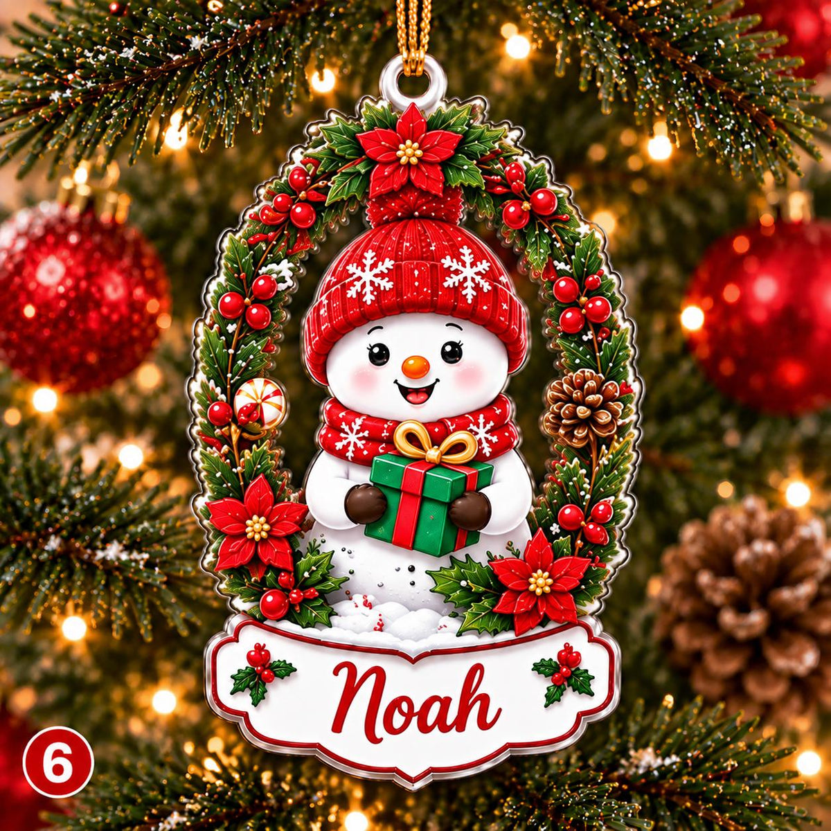 May include: A Christmas tree ornament featuring a white snowman wearing a red knit hat and scarf, holding a green gift box with a gold ribbon. The snowman is framed by a wreath of green pine, red poinsettias, and berries, with the name Noah printed below.