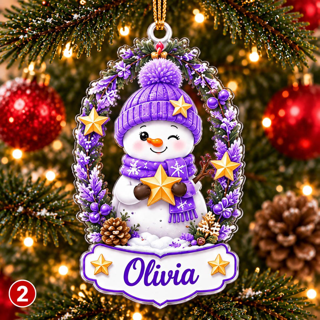 May include: A decorative oval Christmas ornament featuring a white snowman wearing a purple knit hat and scarf, holding a gold star. The snowman is framed by purple floral accents and gold stars, with a white banner at the bottom displaying the name Olivia.