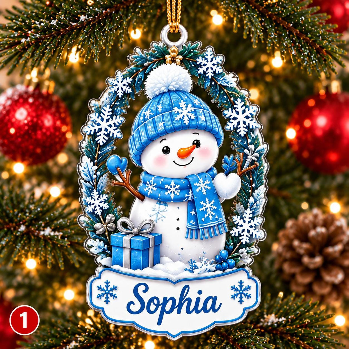 May include: A Christmas ornament featuring a snowman wearing a blue hat and scarf, surrounded by a wreath of pine branches and snowflakes. The snowman holds a blue gift box. A white banner at the bottom displays the name Sophia in blue script.