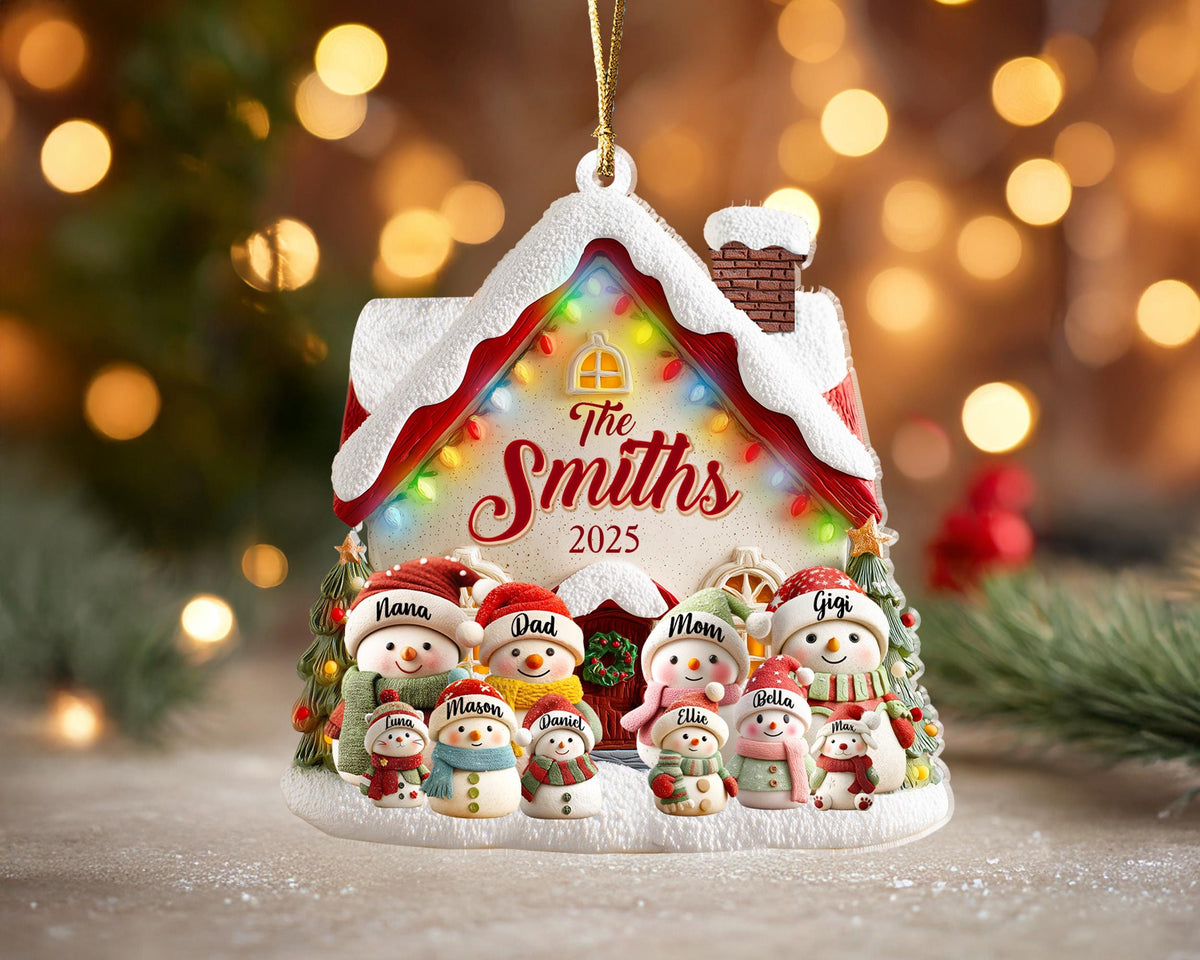 May include: A personalized Christmas ornament shaped like a snow-covered house with the text "The Smiths 2025". The ornament features a family of snowmen, each with a name, and is decorated with colorful lights and a gold hanging string.