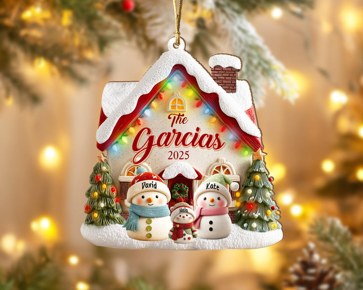 May include: A personalized Christmas ornament shaped like a house, with the text "The Garcias 2025." It features snowmen, Christmas trees, and colorful lights. The ornament has a gold string for hanging.
