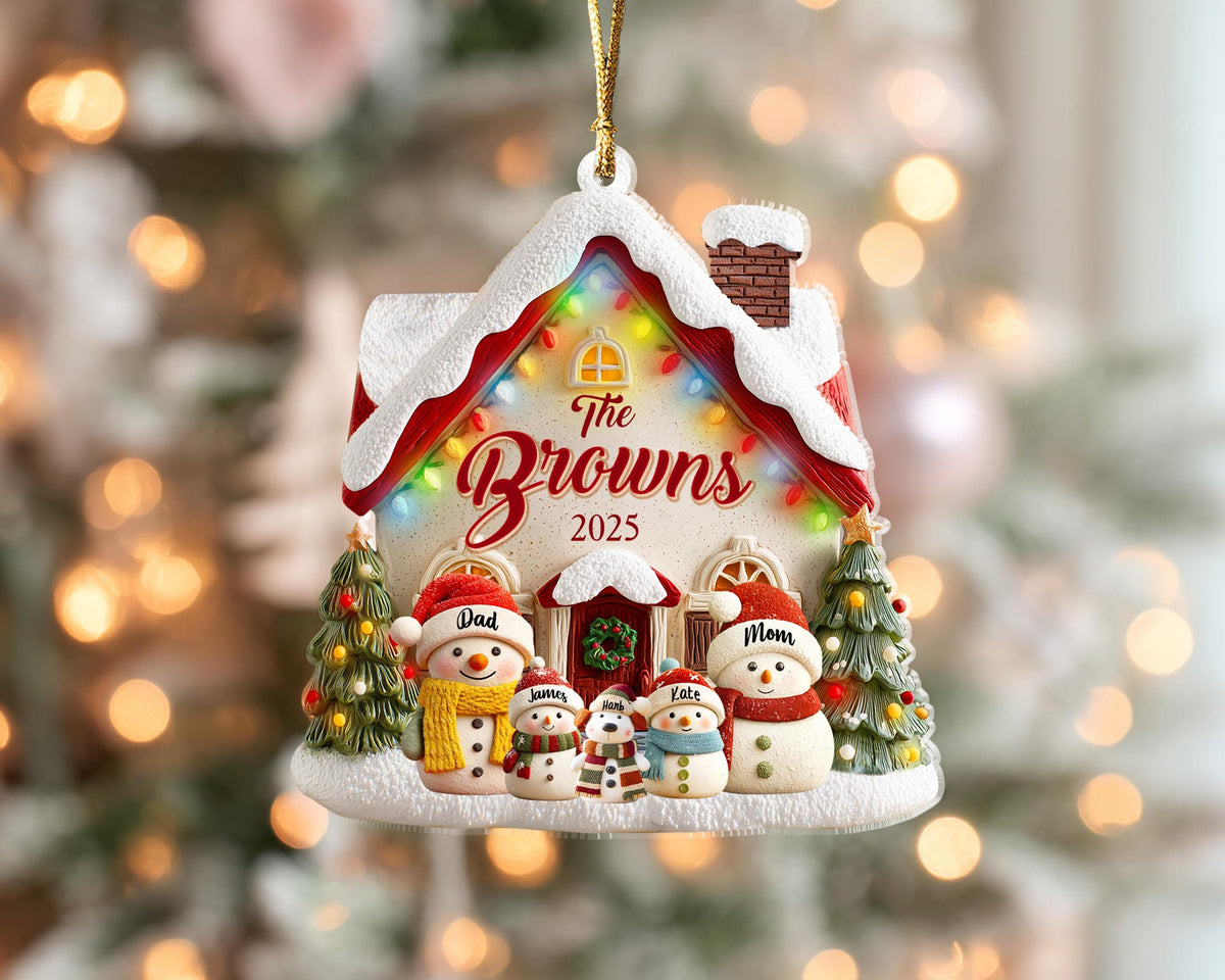 May include: A Christmas ornament shaped like a house, with the text "The Browns 2025". The ornament features snowmen, Christmas trees, and a red roof with snow. The ornament is designed with colorful lights.