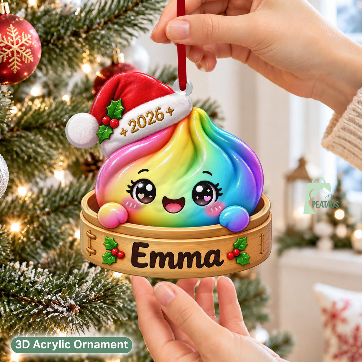 May include: A rainbow-colored dumpling ornament with a smiling face, wearing a red and white Santa hat with the text 2026. The dumpling sits in a wooden steamer basket base featuring the name Emma and green holly leaf accents with red berries.