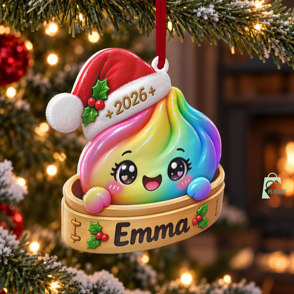 May include: A rainbow-colored dumpling ornament wearing a red Santa hat with a white brim featuring the text 2026. The dumpling sits inside a wooden steamer basket with the name Emma printed on the front, decorated with green holly and red berries.