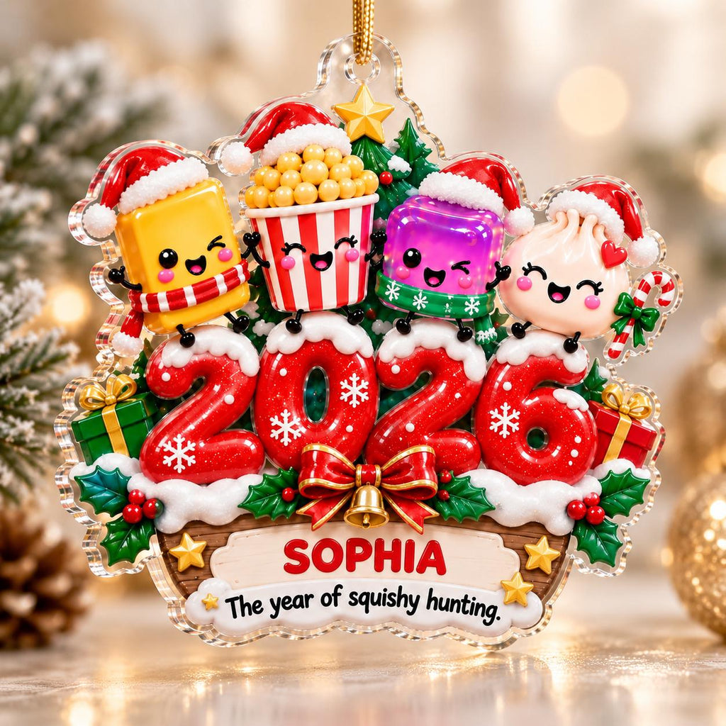May include: A clear acrylic Christmas ornament featuring the red numbers 2026, topped with four cartoon characters wearing Santa hats. Below, a wooden sign displays the name SOPHIA and the text The year of squishy hunting, with holly accents.