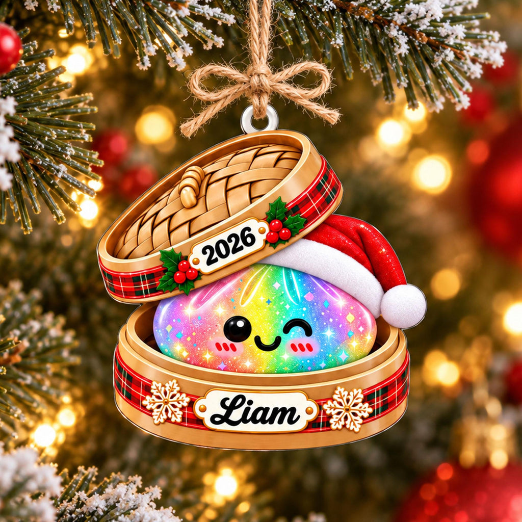 May include: A hanging Christmas ornament featuring a bamboo steamer basket with a red plaid ribbon, holly, and the year 2026. Inside sits a rainbow-colored, sparkling dumpling character wearing a Santa hat, with the name Liam on the base.