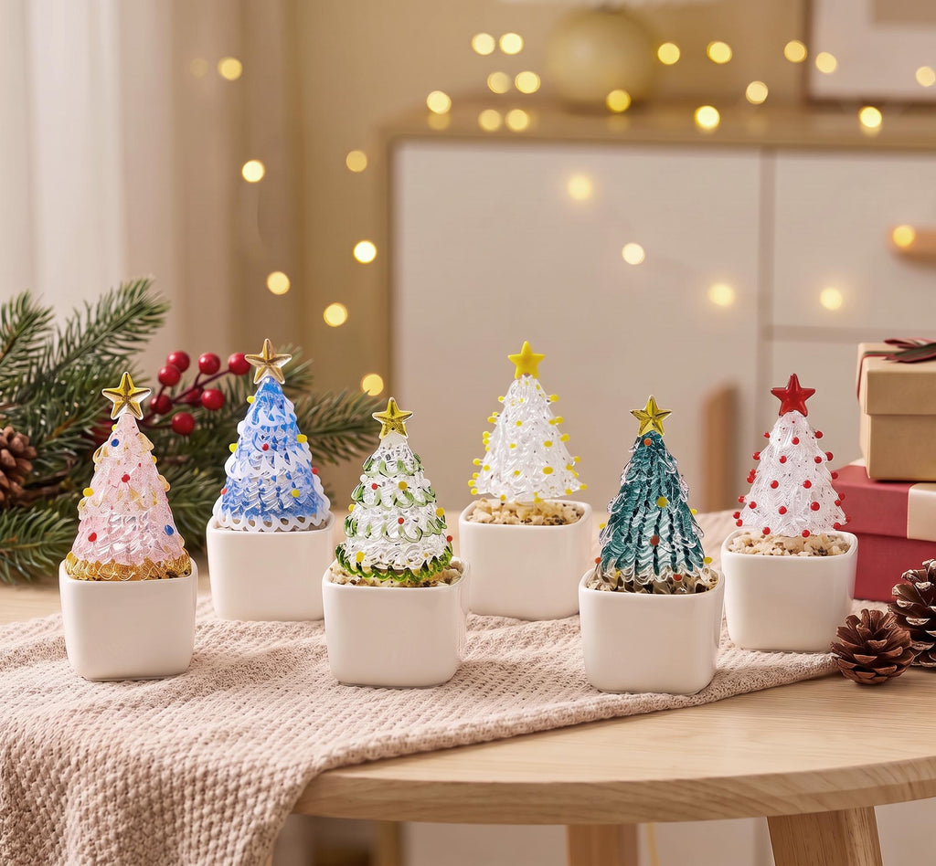 May include: Six miniature glass Christmas trees in white square ceramic pots. Each tree features a textured, colorful glass cone topped with a star, including pink, blue, green, clear, teal, and white versions with small decorative glass beads.