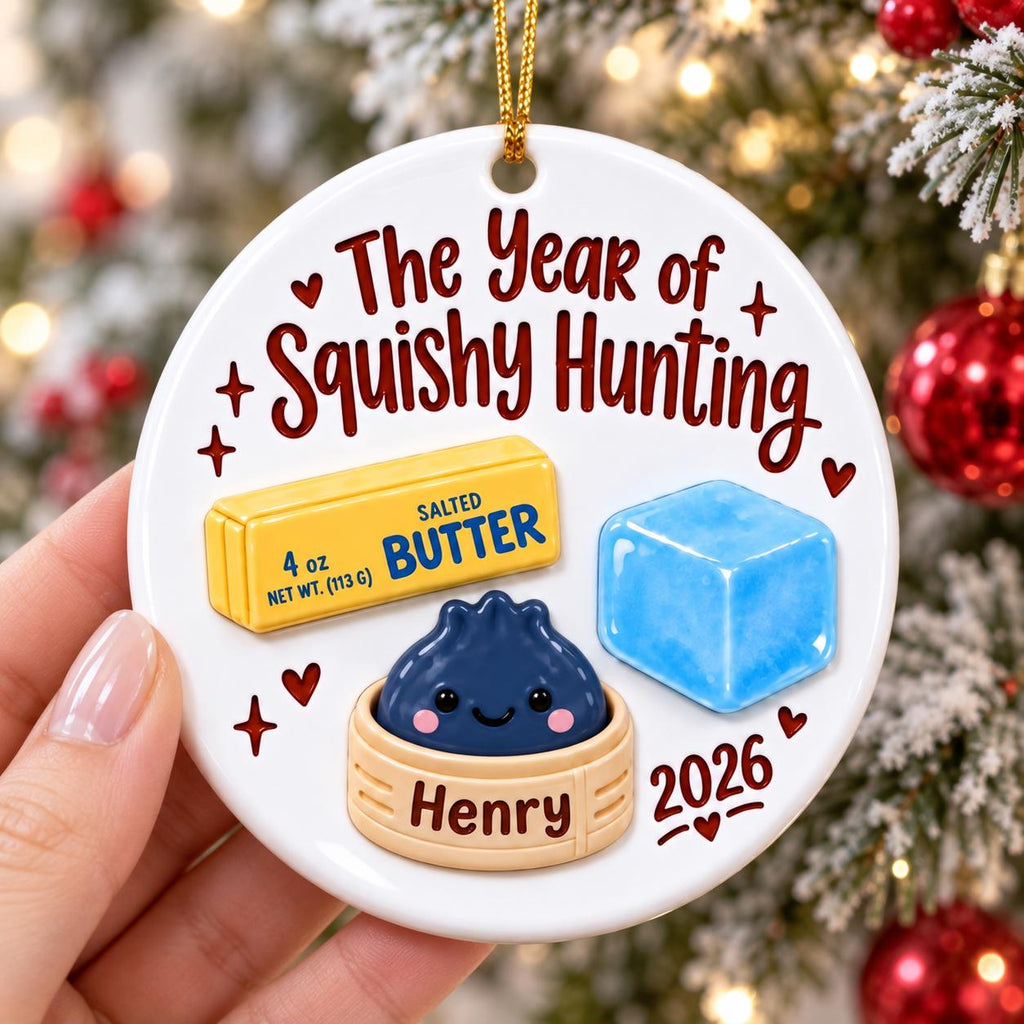 May include: A round white ceramic ornament featuring the text The Year of Squishy Hunting, a yellow stick of salted butter labeled 4 oz, a blue ice cube, and a dark blue dumpling in a bamboo steamer labeled Henry, with the year 2026 printed below.