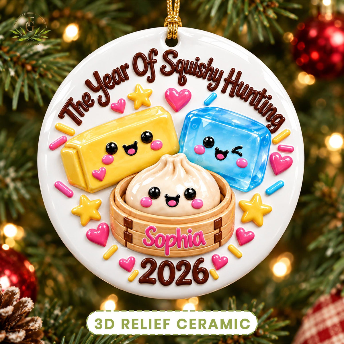 May include: A round white ceramic ornament featuring the text The Year Of Squishy Hunting, Sophia, and 2026. It displays a yellow rectangular block, a blue rectangular block, and a dumpling in a bamboo steamer, all with smiling faces.