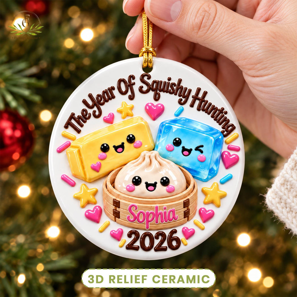 May include: A round white ceramic ornament featuring the text The Year Of Squishy Hunting, Sophia, and 2026. The design includes a yellow rectangular squishy, a blue squishy, and a dumpling in a bamboo steamer, surrounded by colorful hearts and stars.