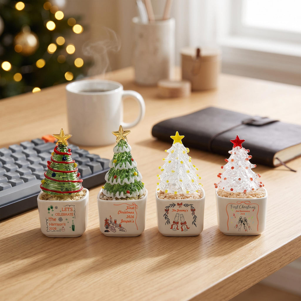 May include: Four small, square white ceramic planters, each holding a miniature glass Christmas tree ornament. The trees feature green or clear glass with colorful accents and a star topper. Each planter displays custom text and festive illustrations.