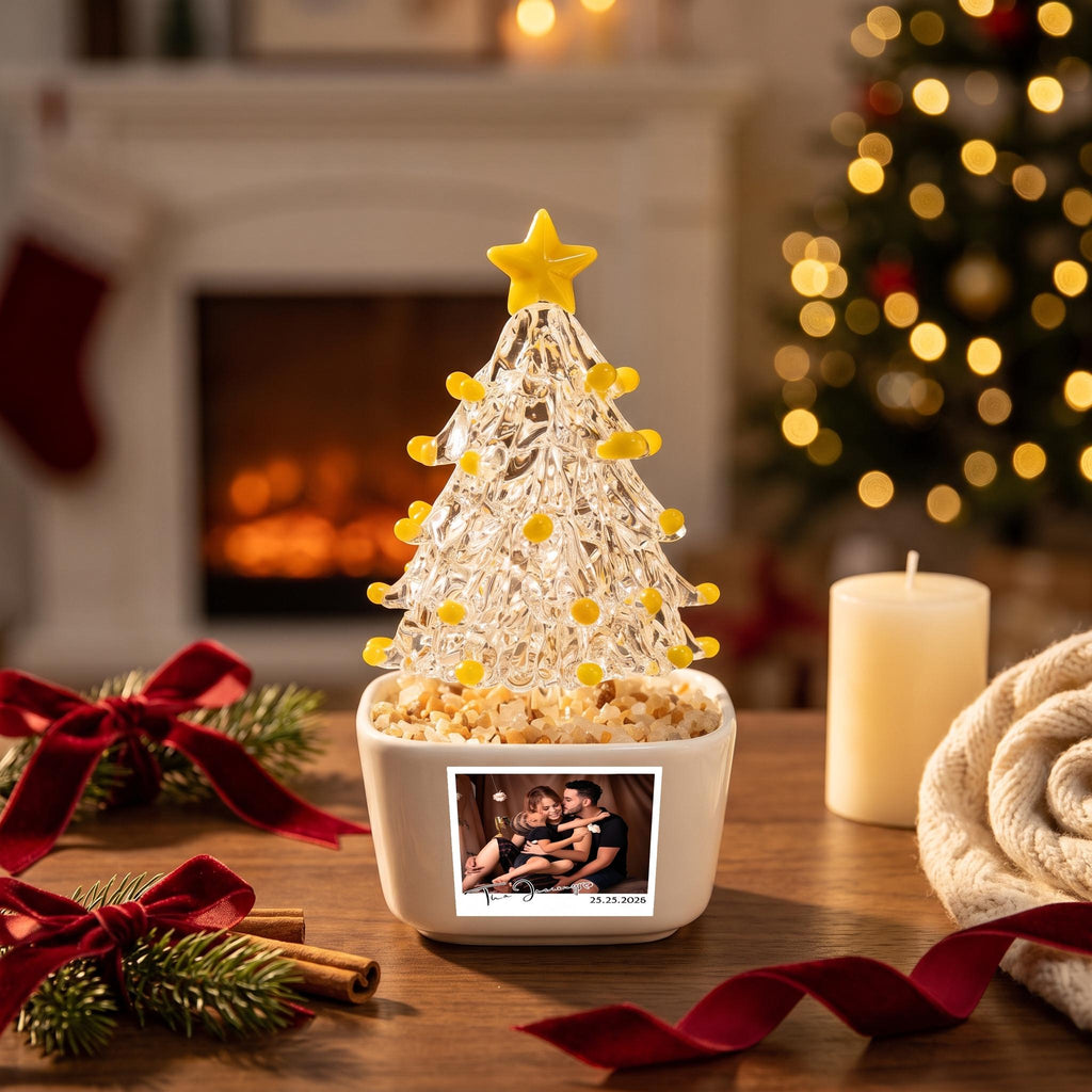 May include: A clear glass Christmas tree ornament with yellow glass accents and a yellow star topper, set in a white square ceramic planter filled with small stones. The planter features a rectangular photo of a couple with the date 25.23.2026.